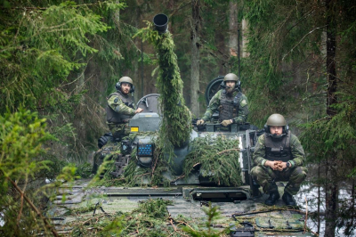 Nomaskējušies NATO daudznacionālās kaujas brigādes vīri un tanks mežā